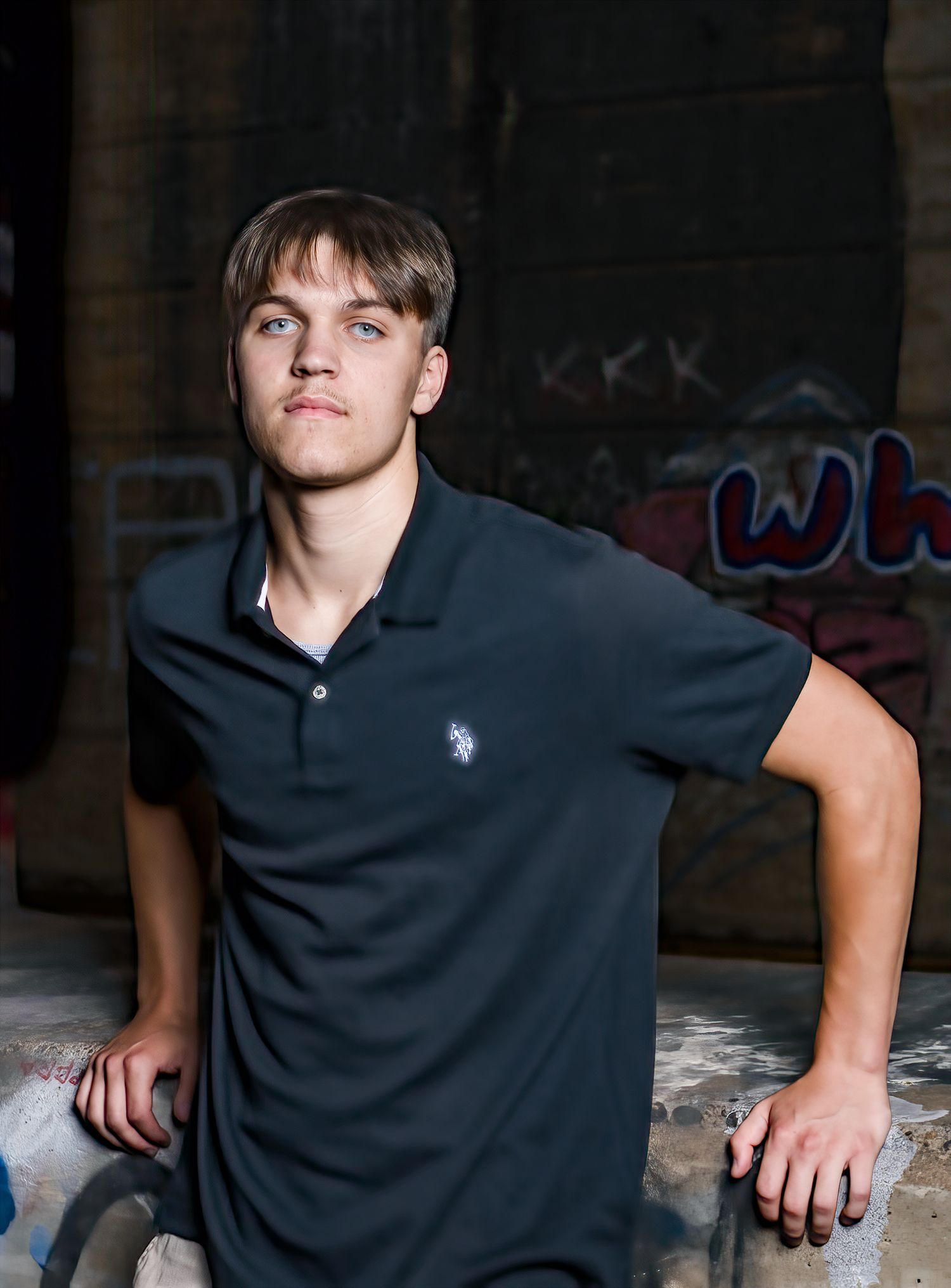 Portrait of young person in navy polo shirt against graffiti background.