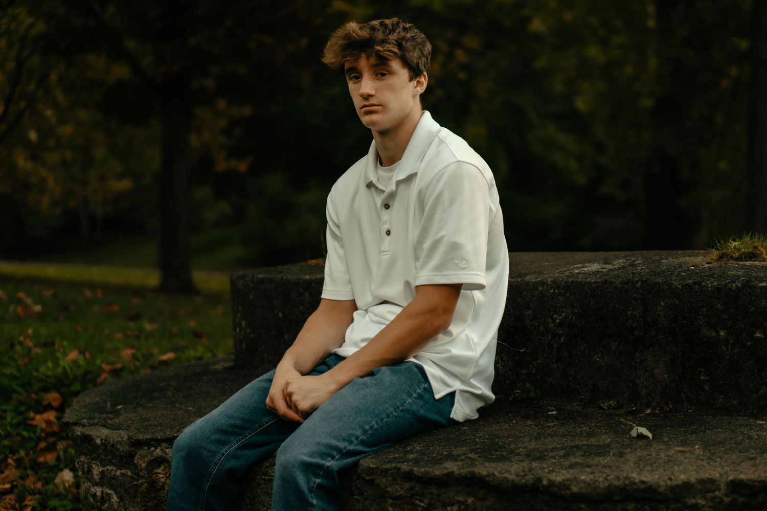 Casual portrait on stone surface in natural outdoor setting with autumn leaves.