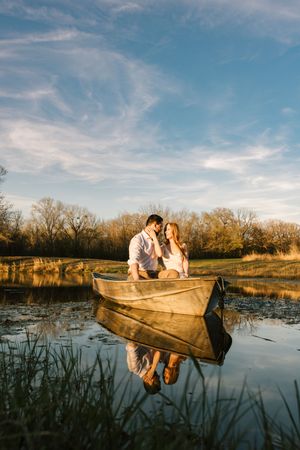 A couple pose in a boat on the pond for their engagement session at Catoosa Sunflower Field in Catoosa, Oklahoma.