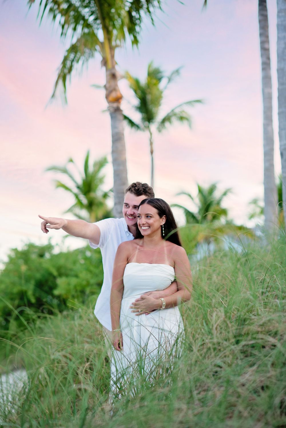 Sunset palm tree photoshoot with couple amongst tall grass during golden hour.