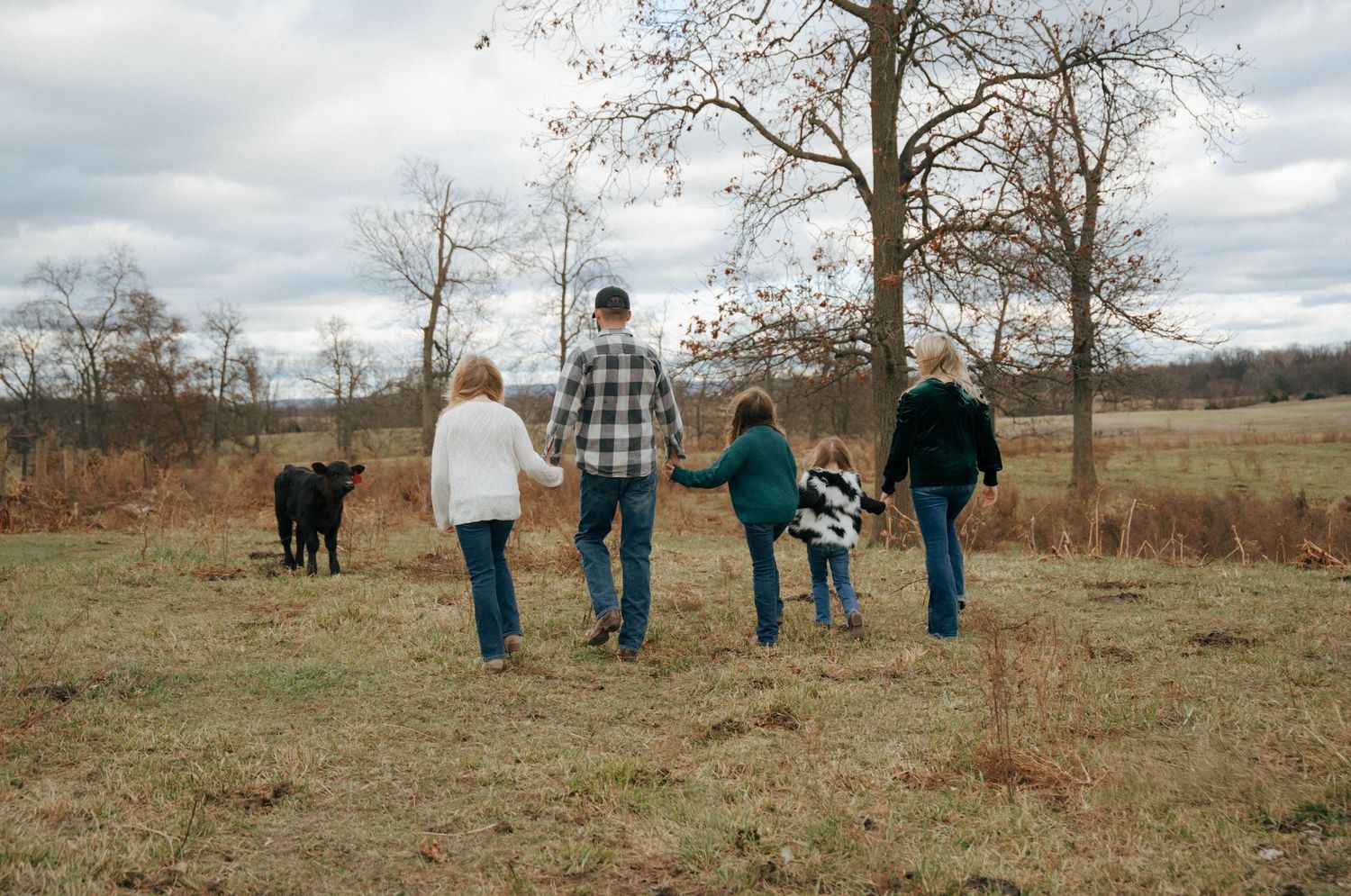 Group walking through an autumn field with bare trees in the background.