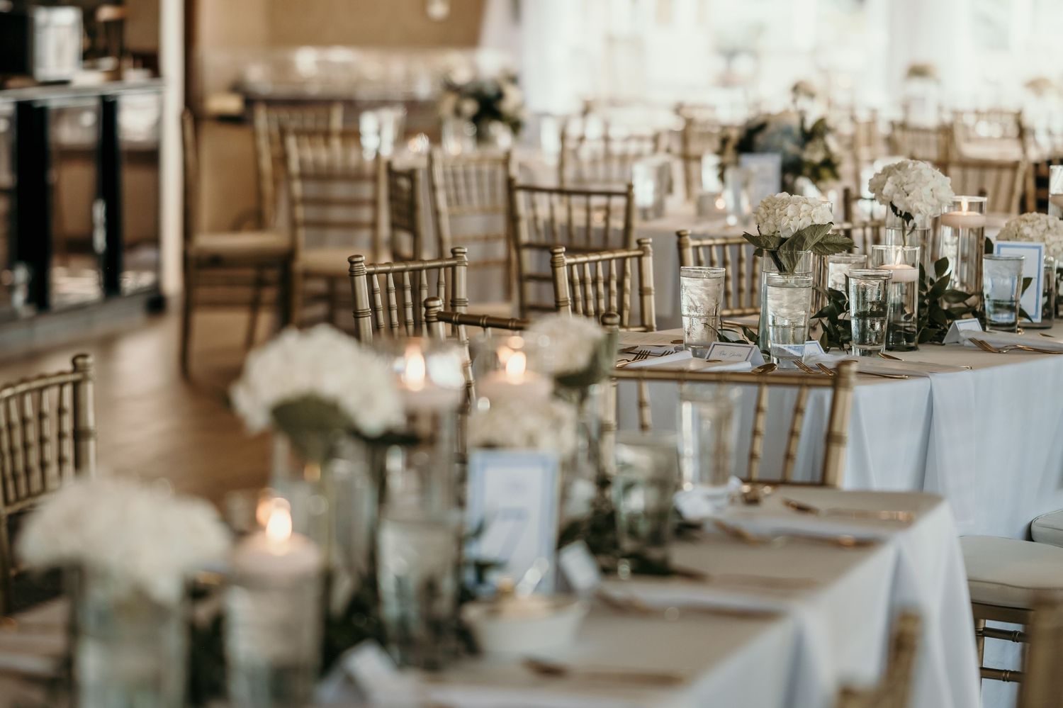 Wedding reception tables set with elegant place settings and natural greenery centerpieces.