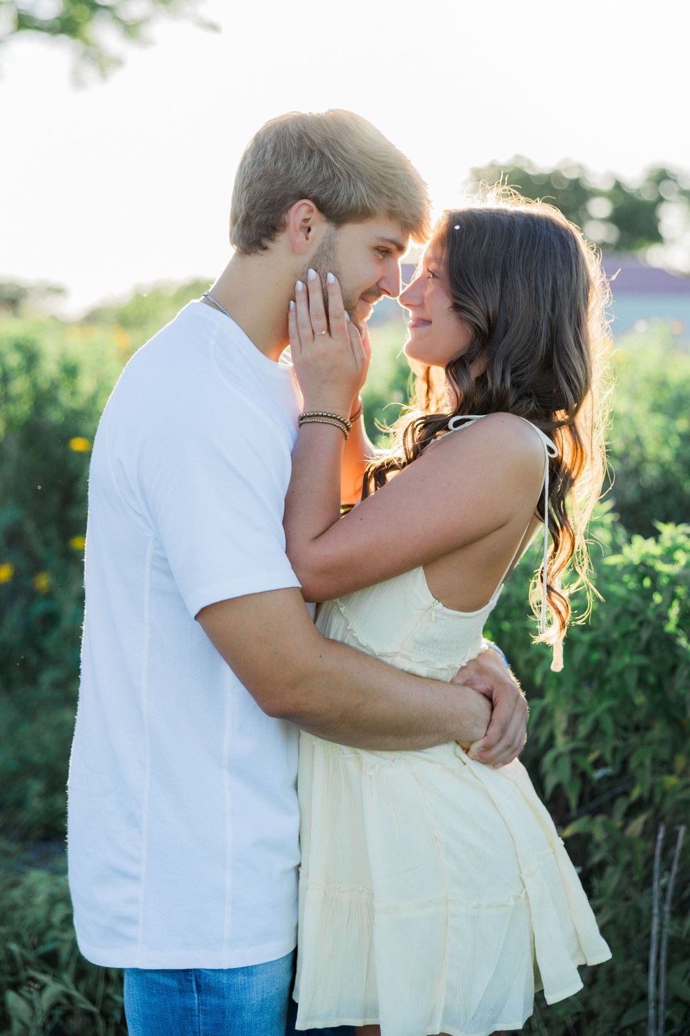Intimate couple sharing tender moment outdoors in casual summer attire.