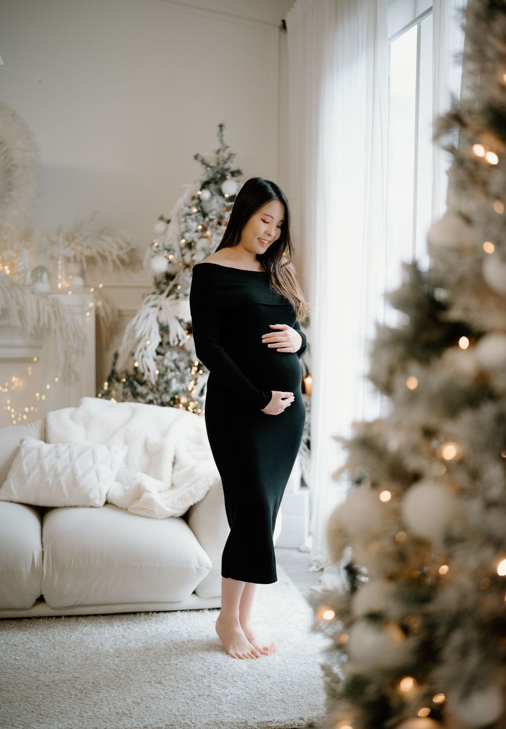 A series of moody holiday photos featuring someone in a black dress posing by a decorated Christmas tree in a bright room.