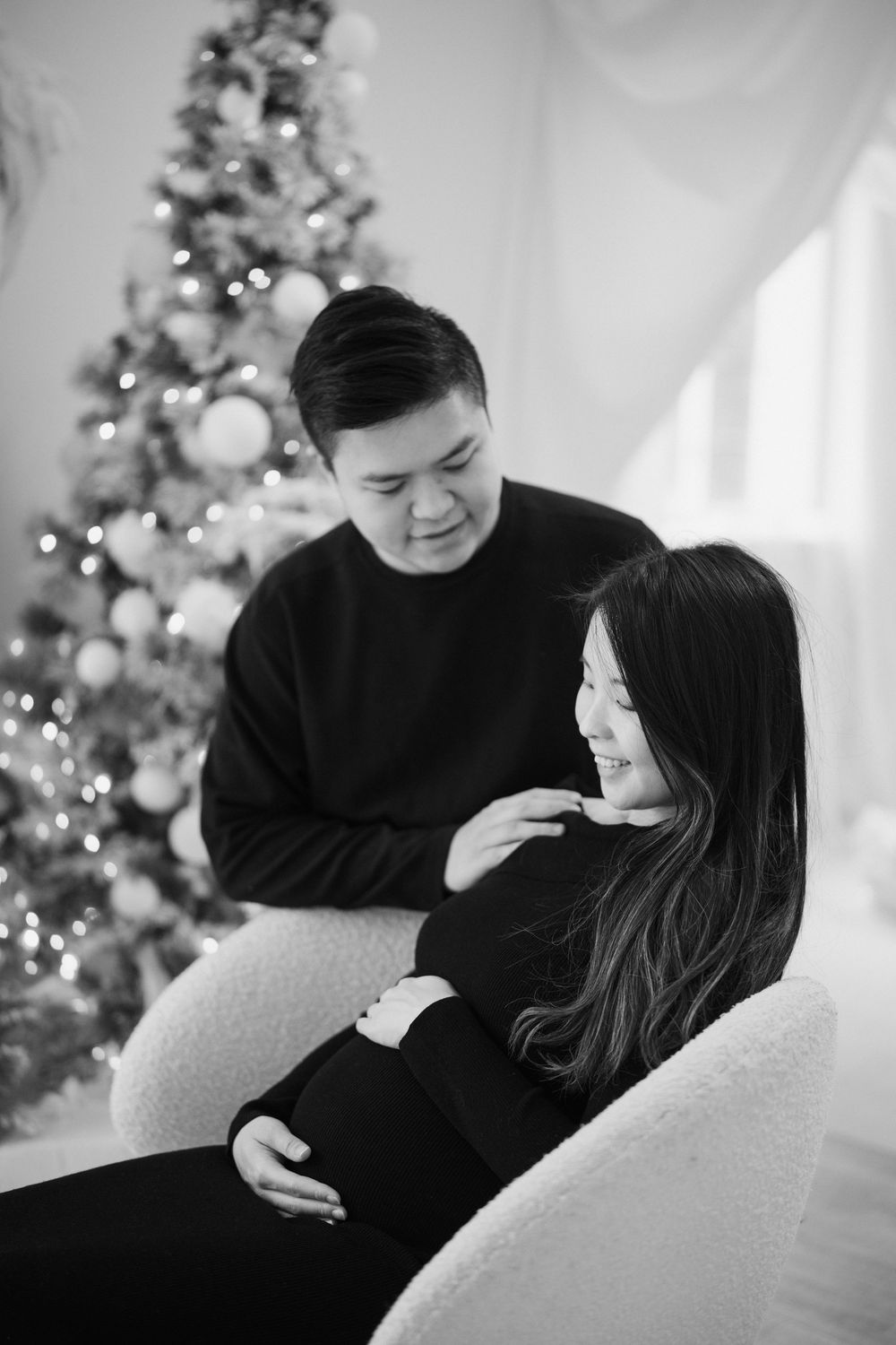 A couple sharing intimate moments in a holiday setting with Christmas trees and lights in the background.