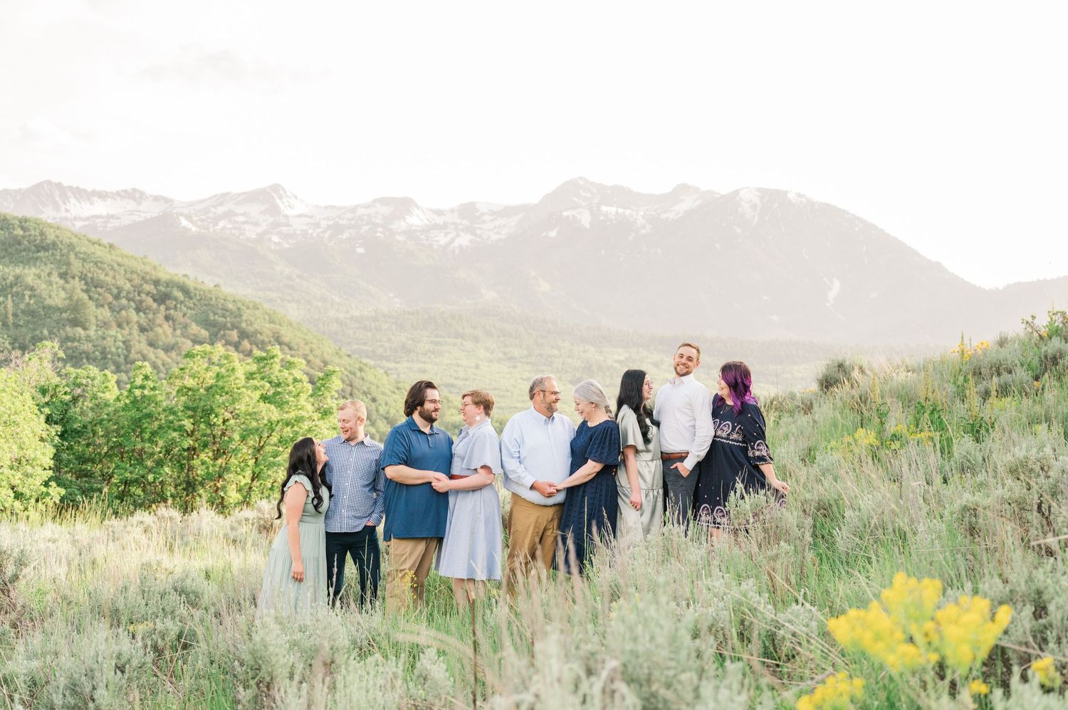 A candid group photo of people gathered on a mountainside with snow-capped peaks in the background.