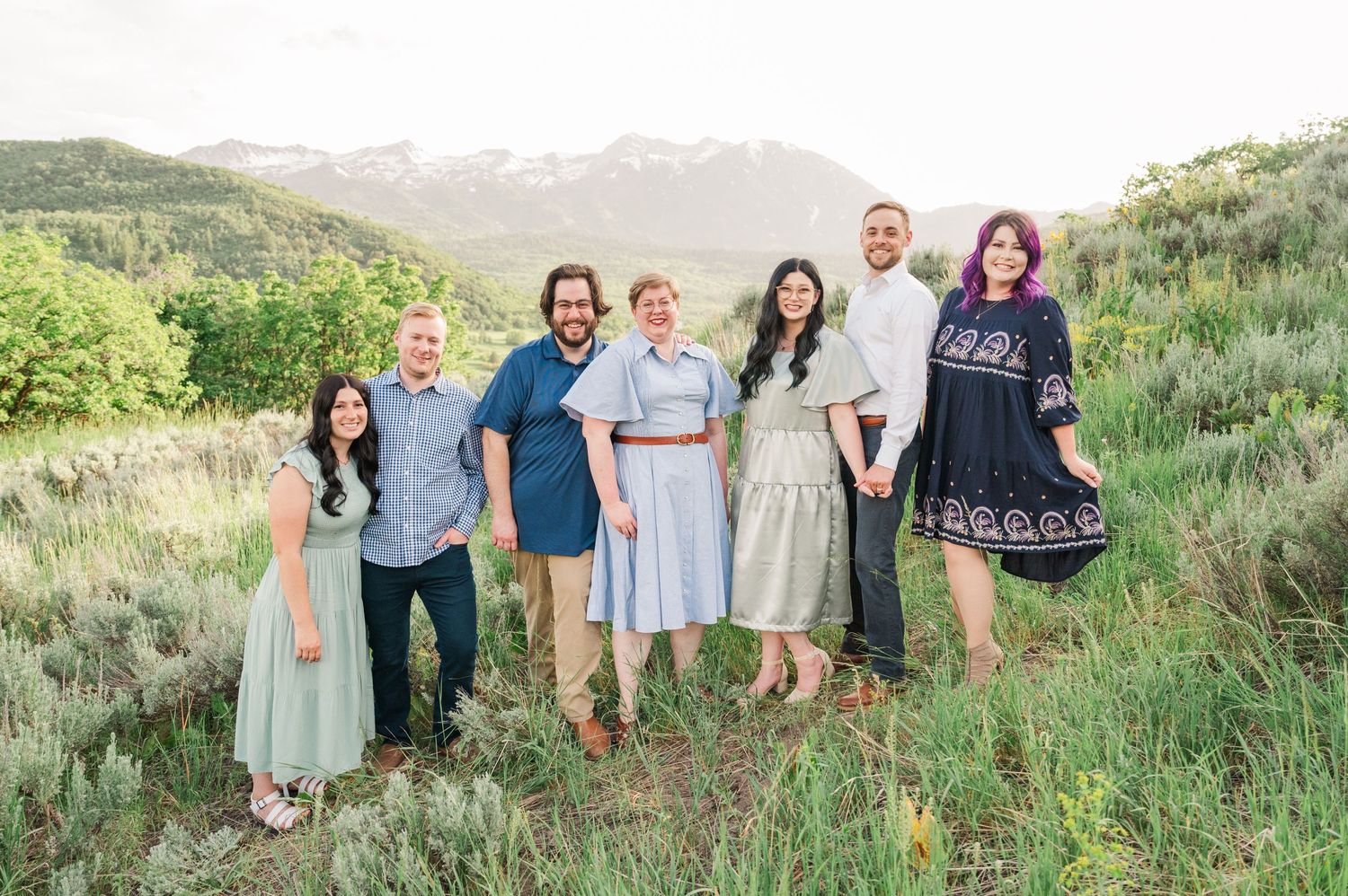 Family group portrait on a hillside with mountains and lush vegetation in the background.