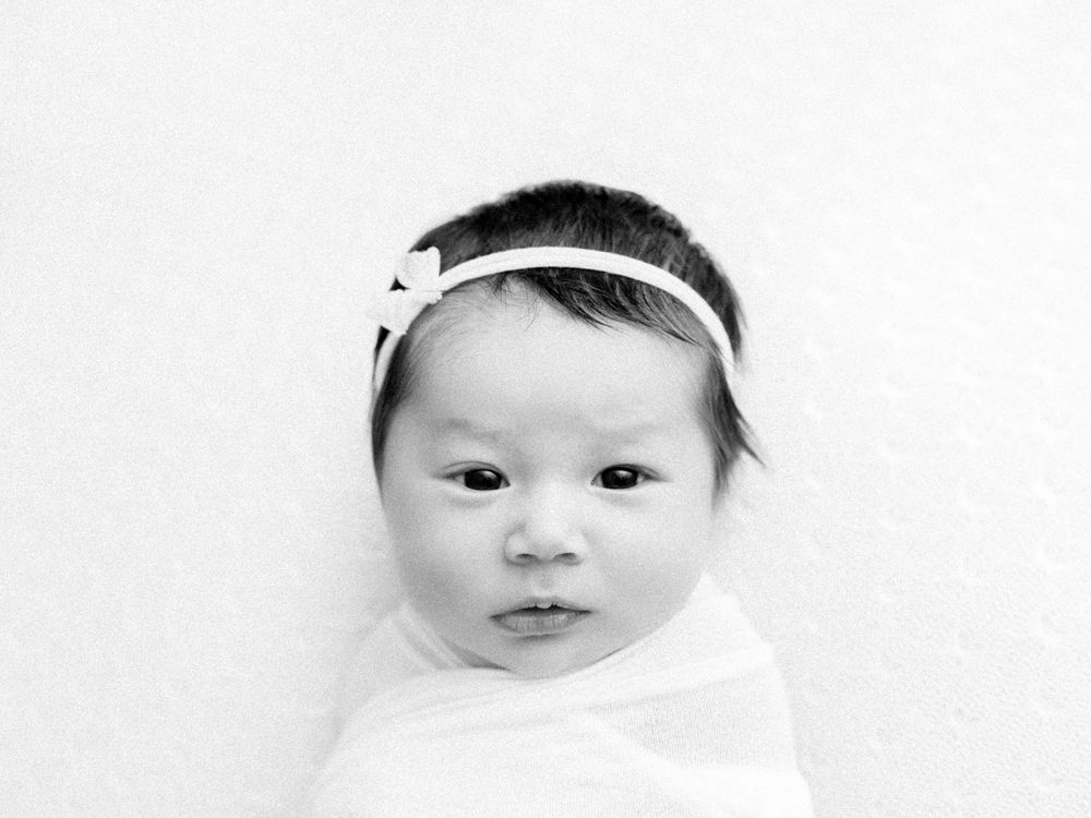 Black and white portrait of infant wearing white headband.