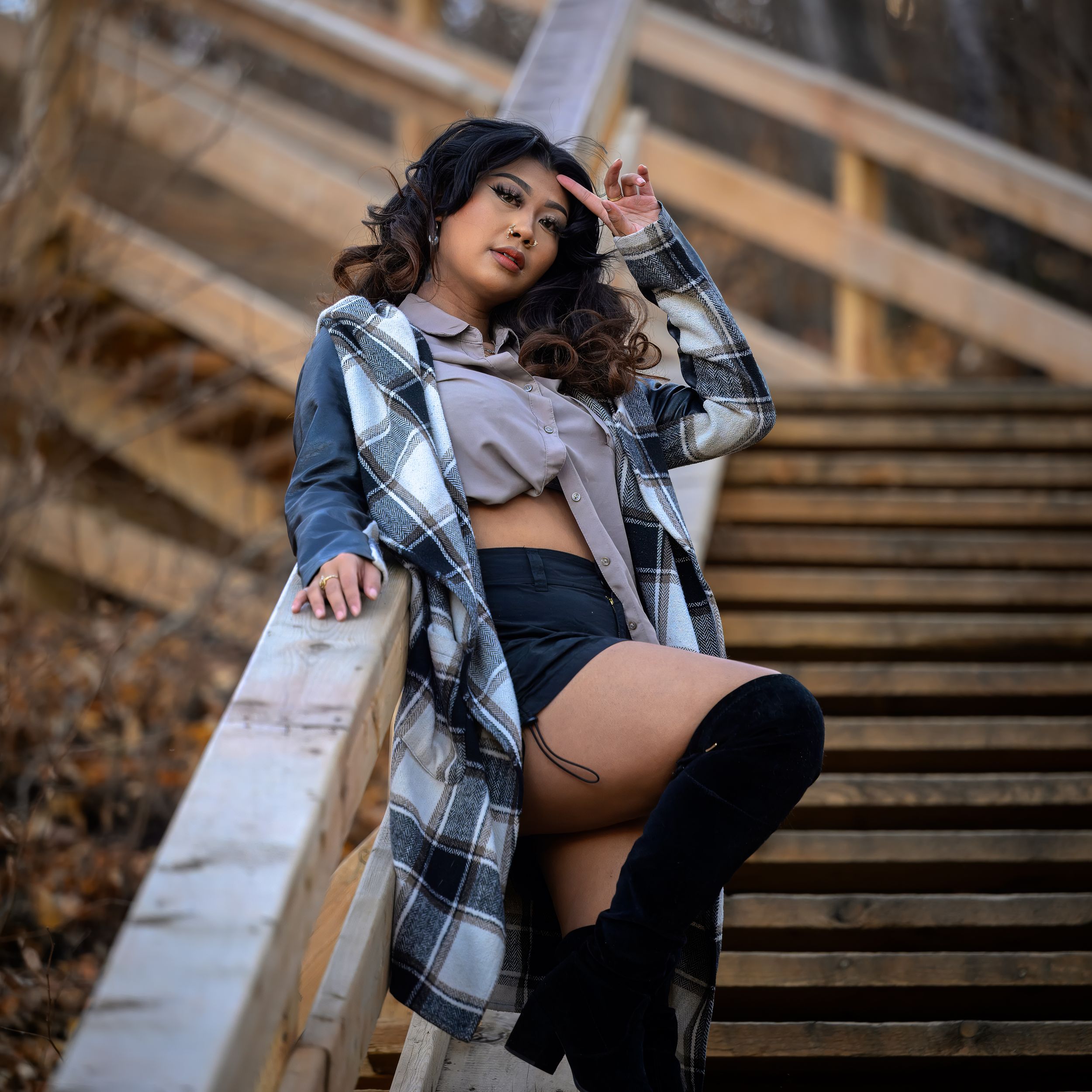 A maternity photoshoot on wooden stairs features a plaid shirt and casual style in warm natural lighting.