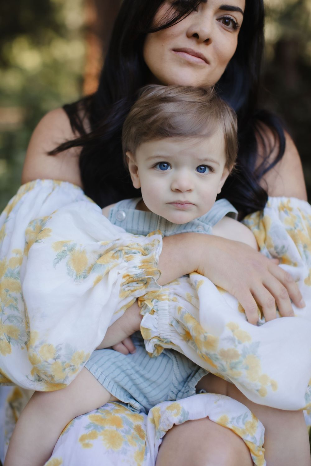 A dark-haired beautiful mother embraces her blue-eyed baby boy tenderly in the forest for a motherhood session. NH-Maine-motherhood-photos
