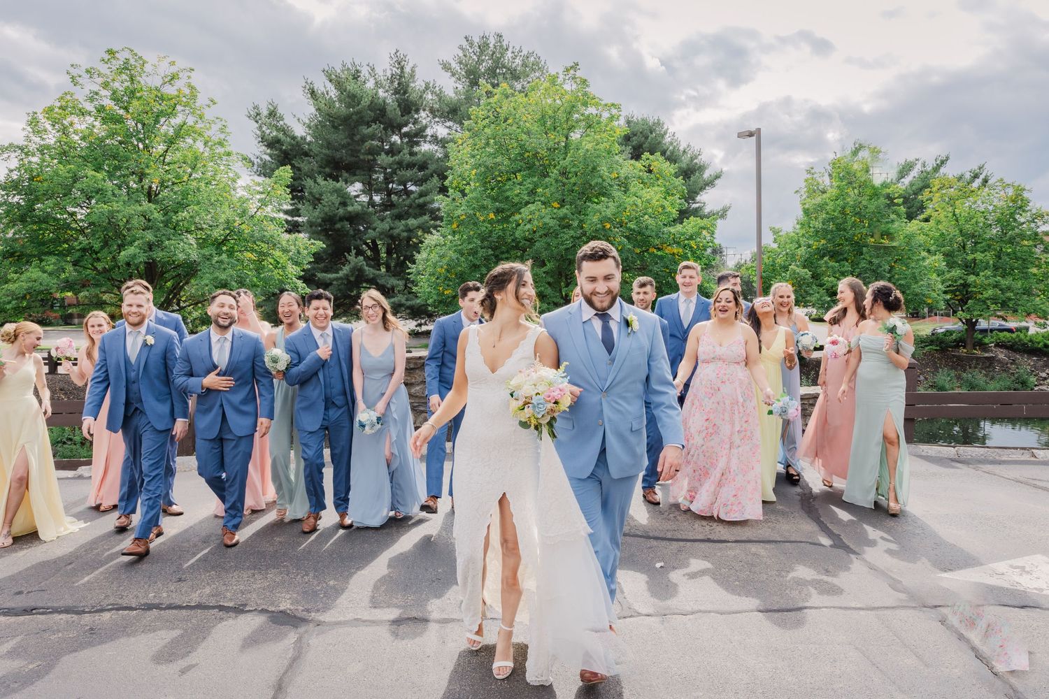 Wedding party walking and celebrating on a paved outdoor area with coordinated attire.