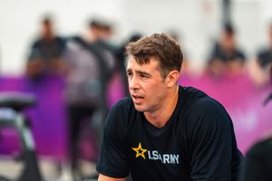 Athlete in US Army black t-shirt resting during outdoor CrossFit competition event.