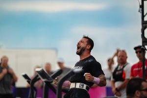 Male CrossFit athlete celebrating victory with fist pump and open mouth roar at outdoor competition.