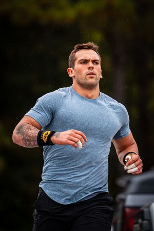 Athletic person in a blue t-shirt and black shorts running outdoors during a workout session.