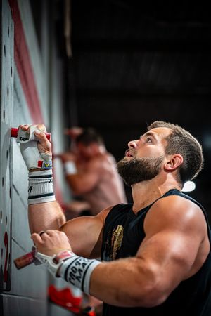 Person performing pull-ups on exercise equipment in a gym setting.