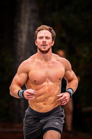 Shirtless athlete sprinting outdoors during an intense training session.