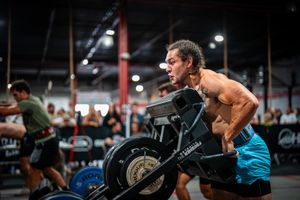 Athletes working out with rowing machines in a CrossFit gym setting.