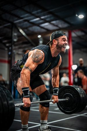 Athlete performing barbell deadlift with proper form in gym environment.