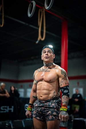 Tattooed athlete working out shirtless in indoor gym setting.