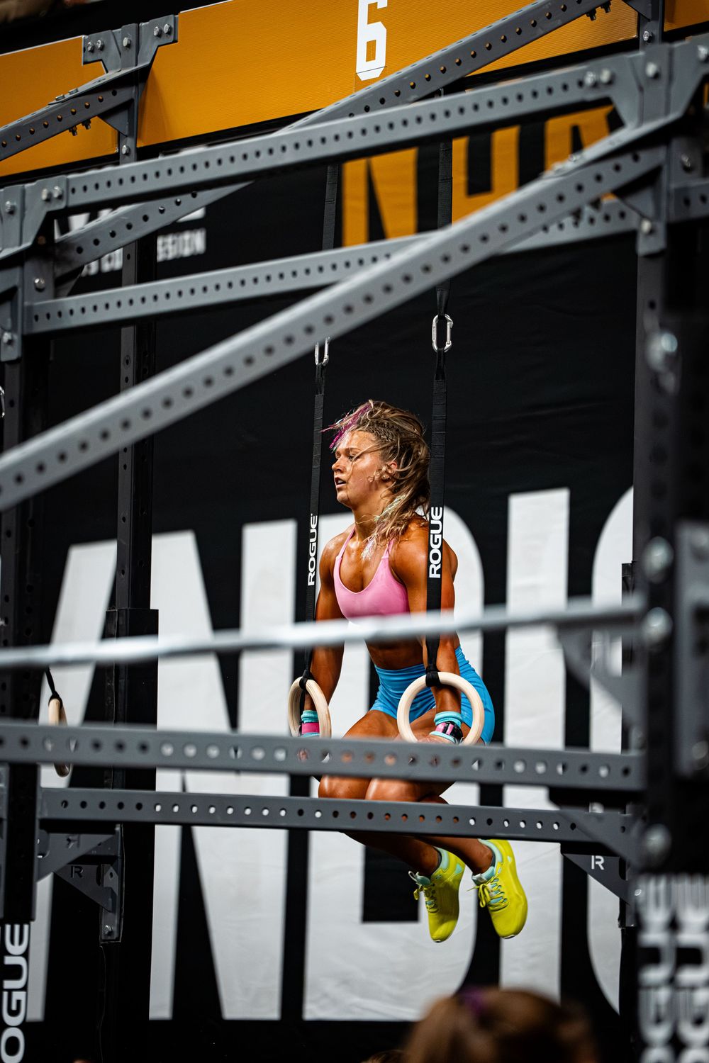 Athletes perform intense pull-ups on gymnastic rings during a CrossFit competition.