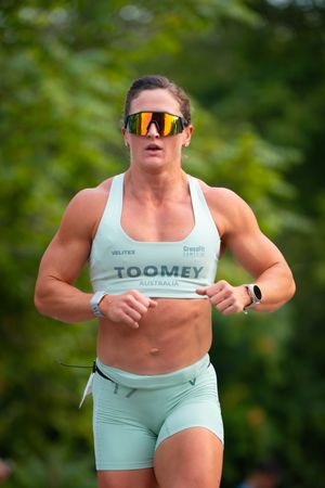 Female athlete in mint workout gear running outdoors with determination.