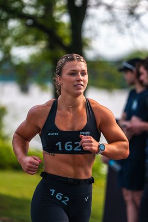 Strong athlete in black sportswear sprinting during outdoor competition.