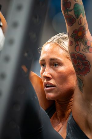 Close-up profile view of an athlete with colorful tattoos during an intense CrossFit competition.