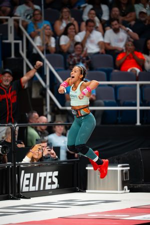 CrossFit athlete performing an explosive box jump movement at a competition event.