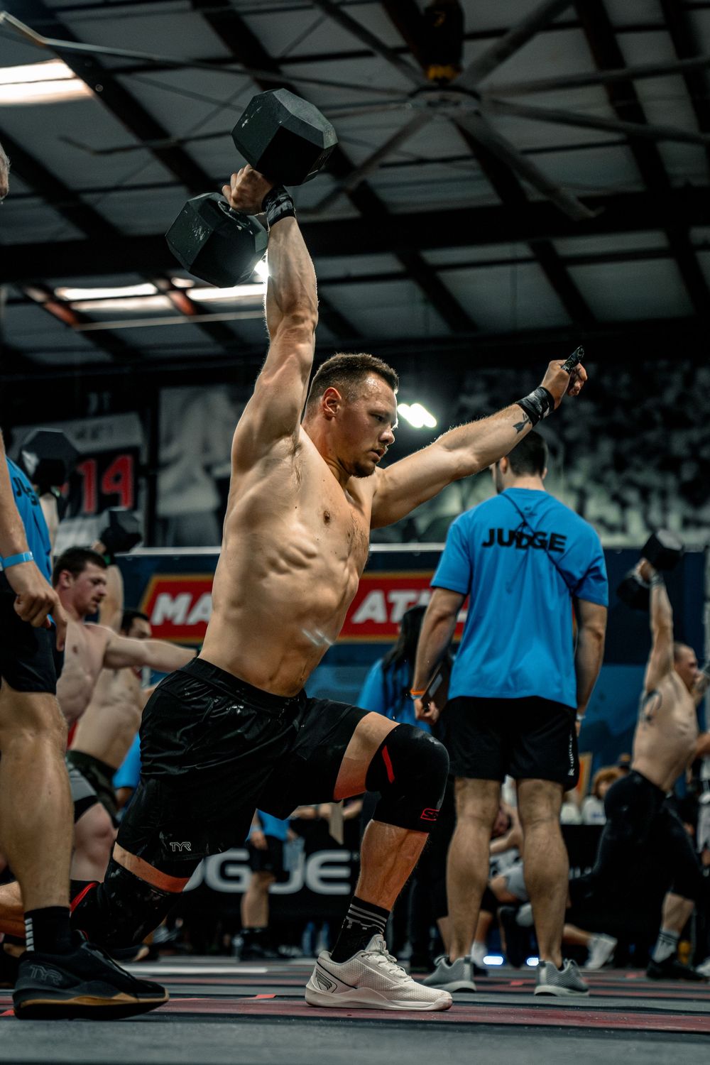 Athletes performing synchronized floor exercises during indoor CrossFit competition.