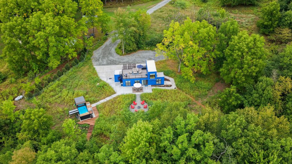 Aerial view of a natural gas well pad surrounded by lush green trees and forest in a rural setting.