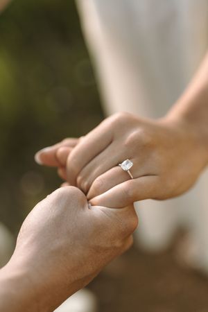 Six cropped photos show hands touching in intimate gentle poses with a diamond engagement ring on a finger.