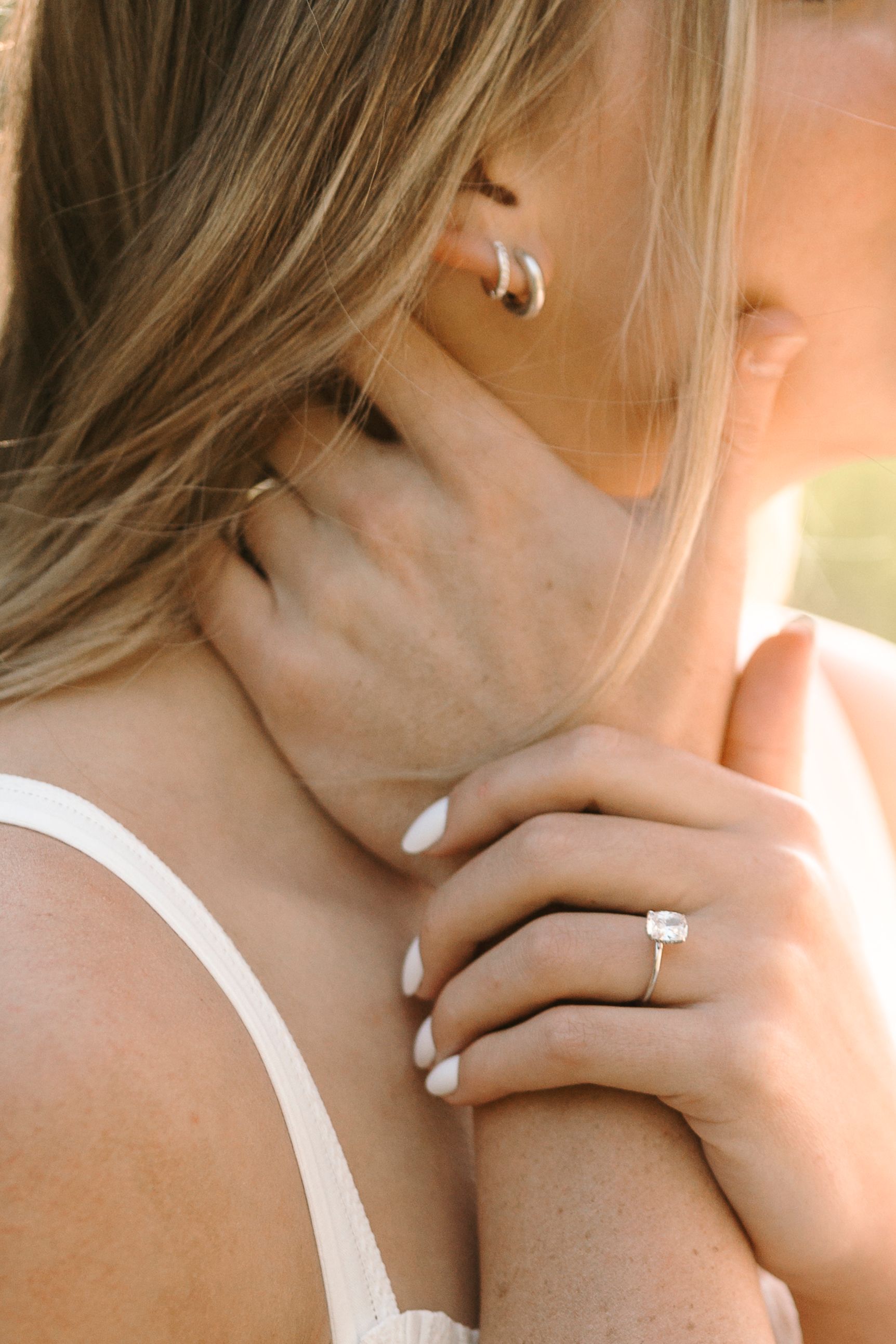 A series of cropped close-up photos showing a silver necklace or pendant against skin and a white garment.