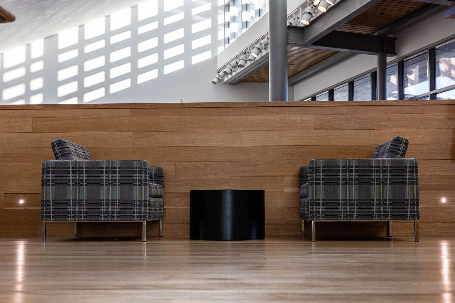 Modern lounge area with two plaid armchairs and wooden floors in a minimalist setting.