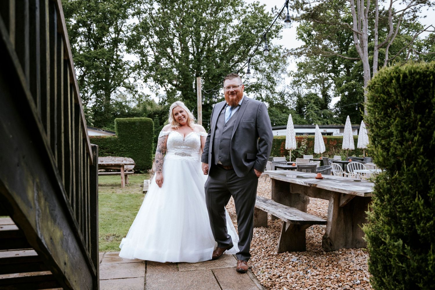A couple walks together on a garden path with rustic wooden benches.