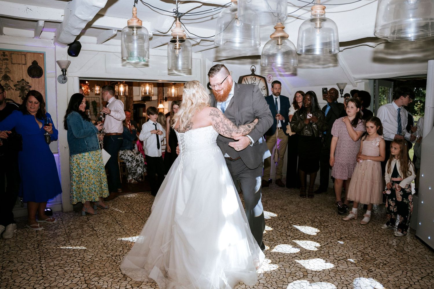 A couple dances under hanging mason jar lights at their wedding reception.