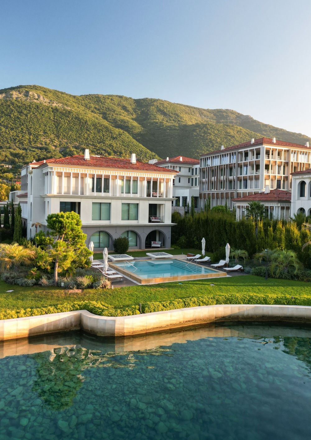 Luxurious Mediterranean-style resort with pool overlooking mountain landscape.