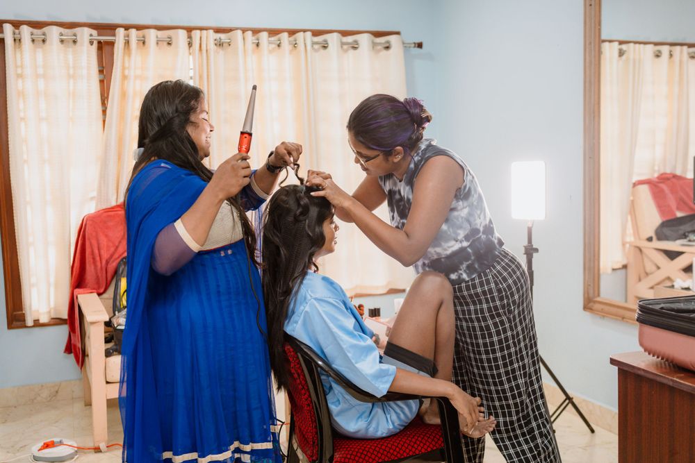 Stylists work on hair preparation during a wedding getting ready session in a blue room.