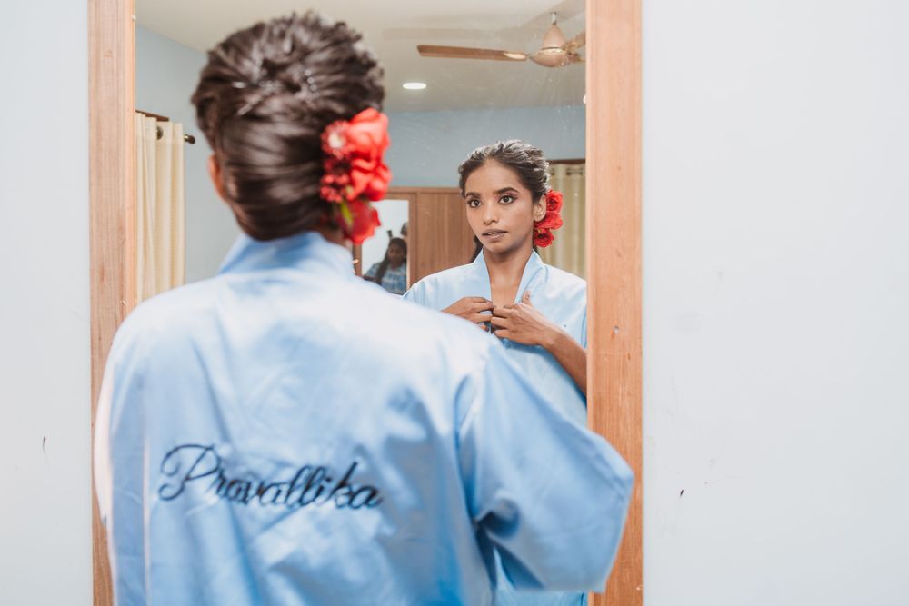 Reflection in mirror shows completed bridal hair with red flower accent.