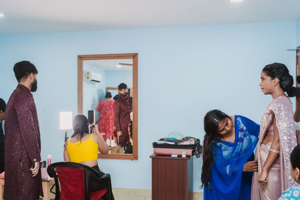Wedding preparation room with multiple people getting ready and a large mirror.