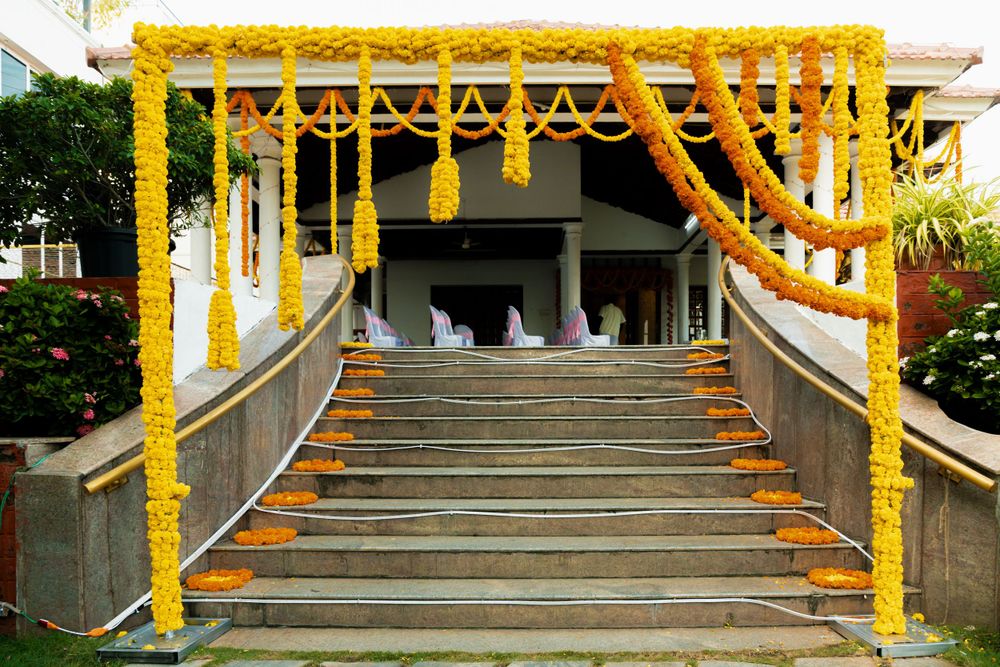 Traditional Indian wedding entrance decorated with bright yellow marigold flower garlands and drapes.