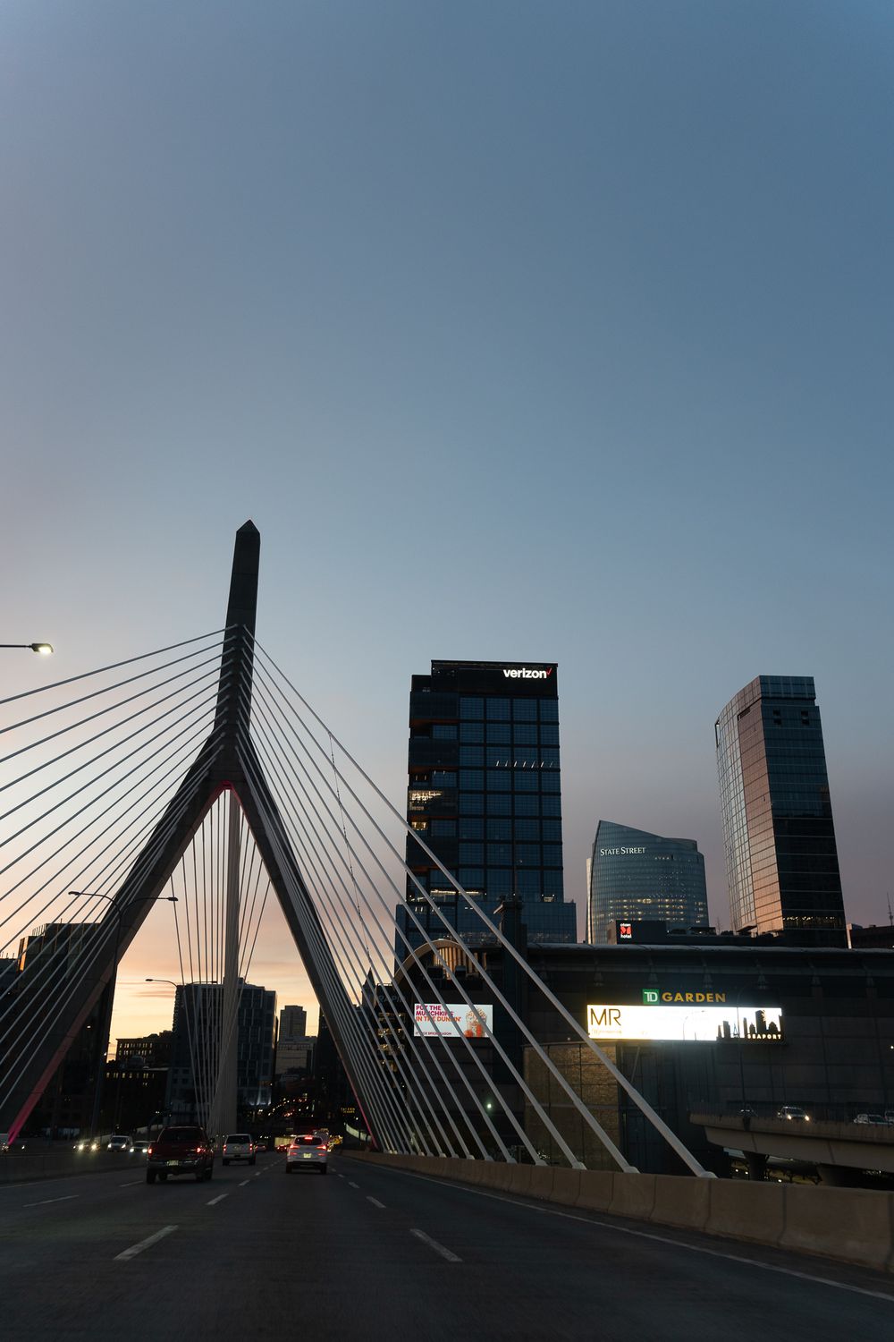 The Zakim Bridge and Boston skyline at dusk with modern office towers in the background.