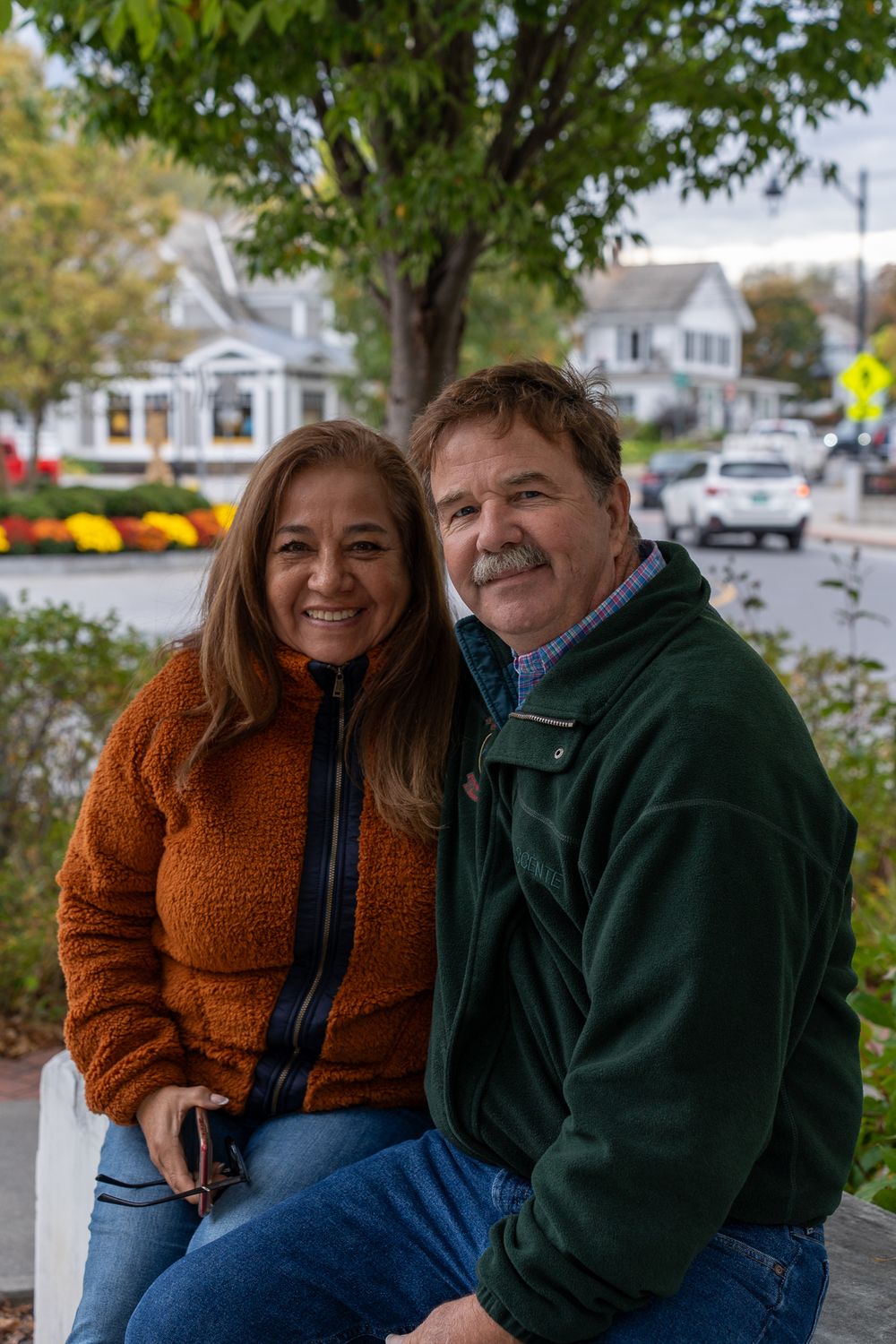 Couple sitting together outdoors in autumn wearing cozy sweaters.