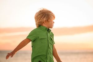 Person in bright green clothing walking on beach during golden hour.