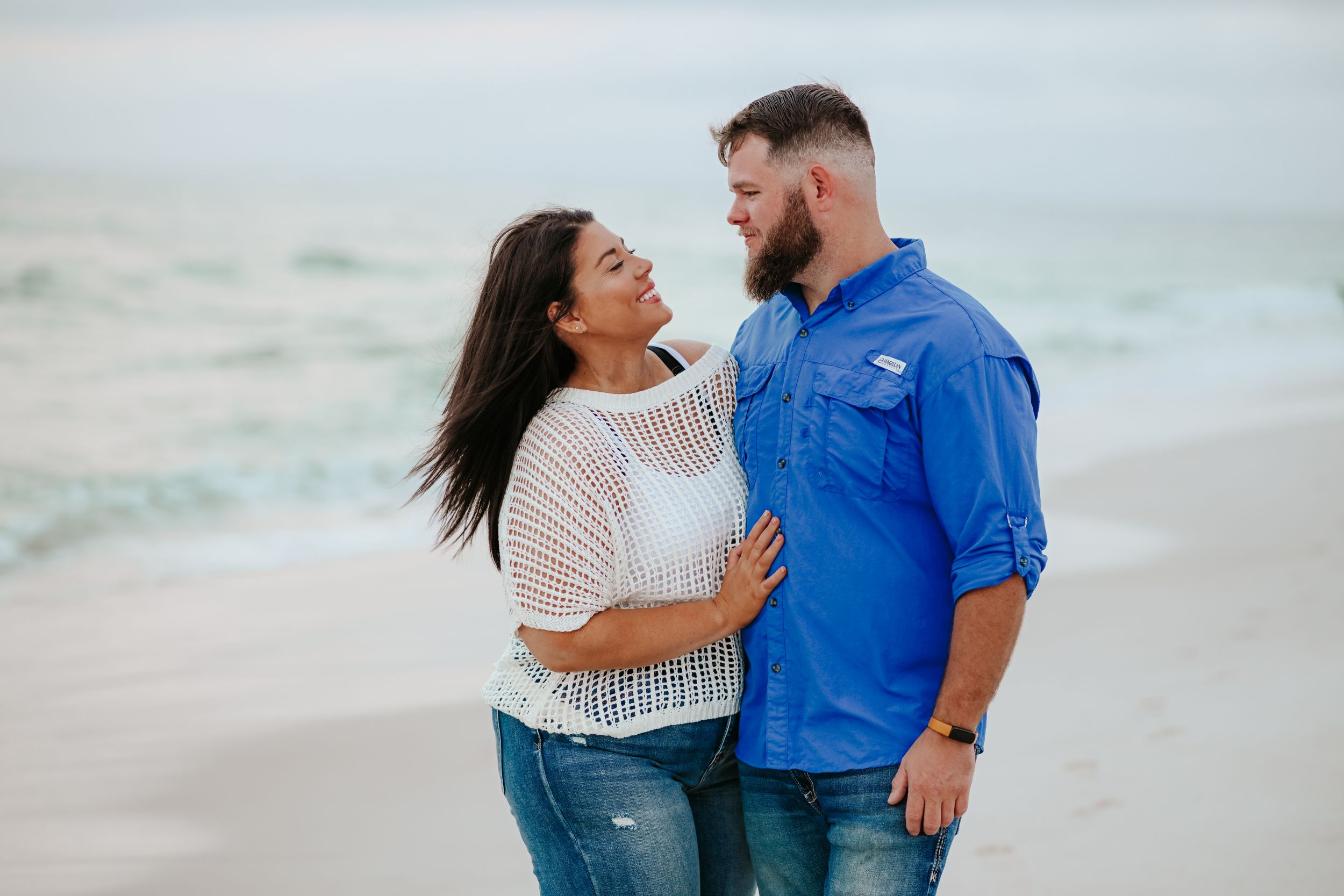 A couple shares a tender moment together on a beach during a sunset photo session.