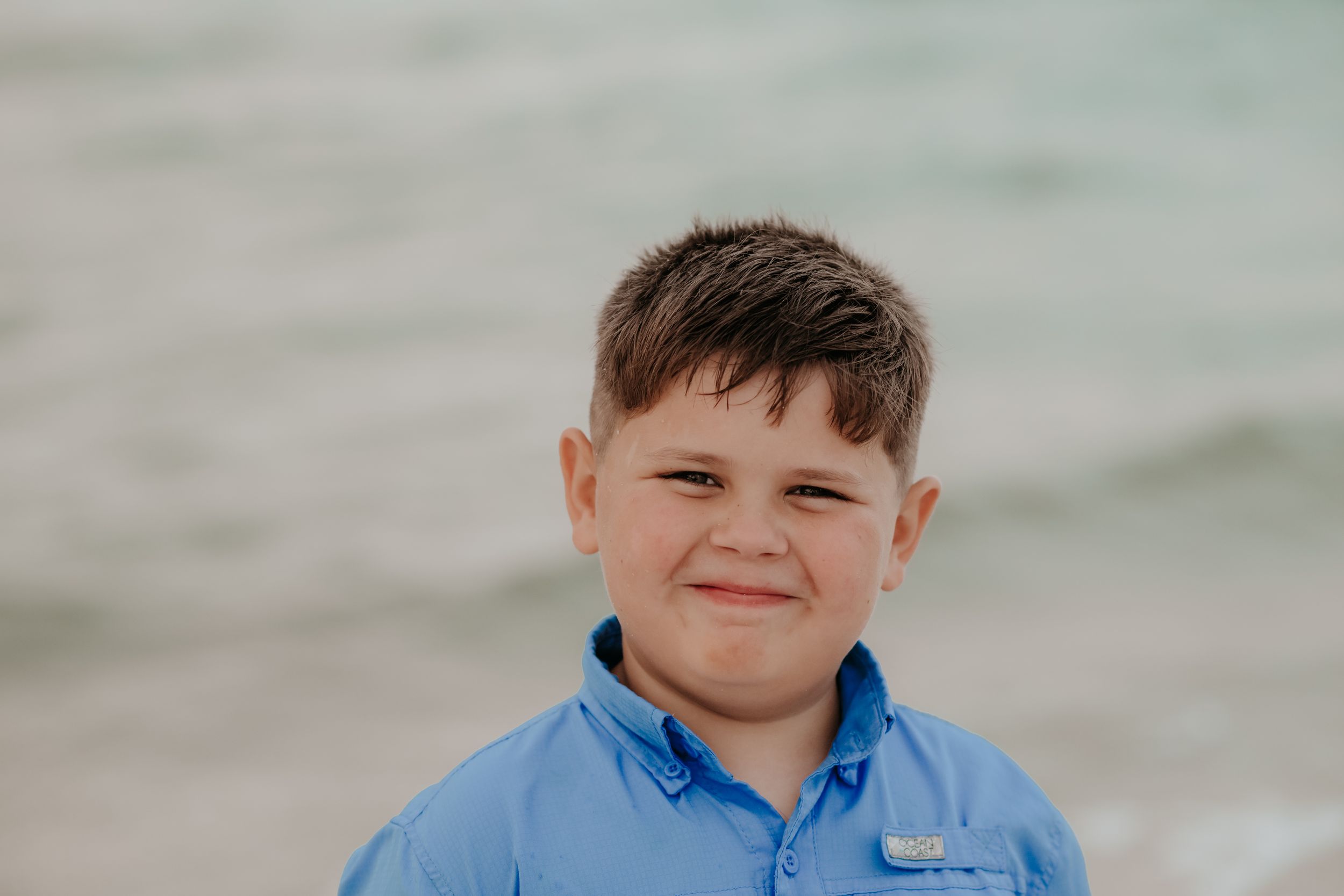 Close-up portraits of children smiling at the camera during a beach photo session.