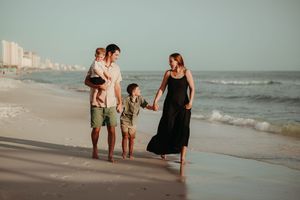 Group walking along beach shoreline during evening light.