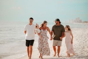 A group walks together on a pristine beach with gentle waves rolling in.