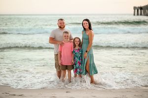 Family enjoys beach time together near ocean waves at sunset.