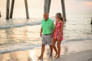 Family members walk along shoreline during golden hour beach photo session.