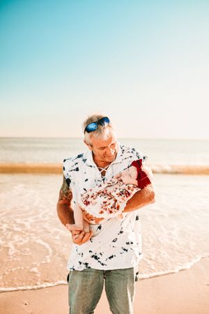 Person in a patterned shirt playing in the ocean surf at sunset.